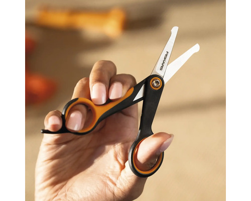 Mână ținând o foarfecă mică marca Fiskars