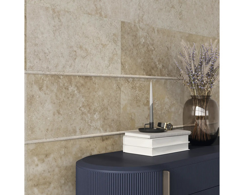 Plăci de perete bej cu bandă decorativă, combinate cu o piesă de mobilier închisă la culoare, un vas transparent de sticlă cu flori, cărți și o lumânare.