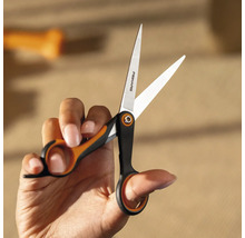 O mână ține o foarfecă Fiskars.