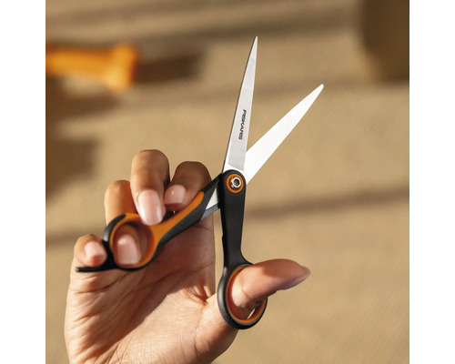 O mână ține o foarfecă Fiskars.