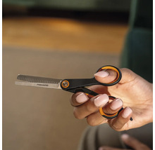 O mână ține o foarfecă de filat marca Fiskars.