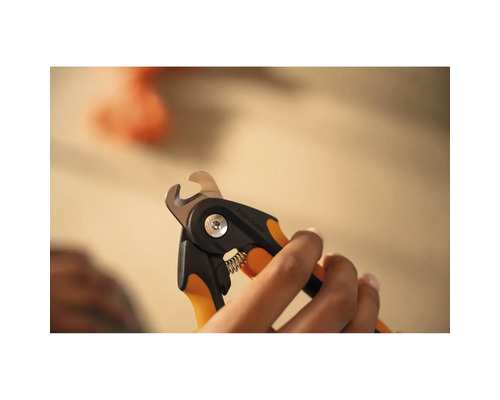 Mâini care țin un clește de gheare pentru animale de companie