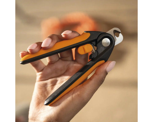 Mâna ține o pereche de foarfeci de unghii pentru animale cu mânere