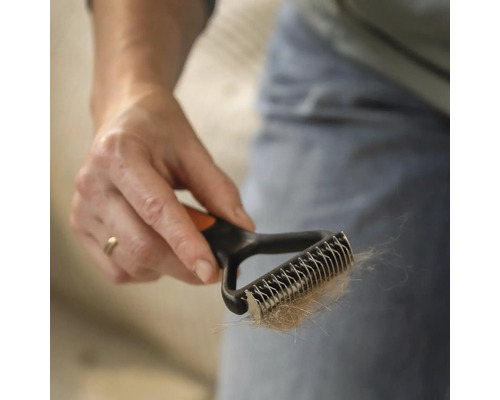 Mână ținând o perie pentru păr de animale cu păr de animale