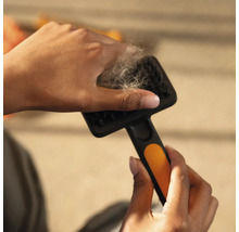 Mâini îndepărtând păr de animale de pe o perie pentru animale