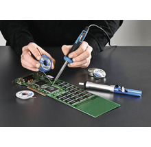 O persoană sudează o placă de circuit imprimat cu un pistol de lipit, cositor de lipit și o pompă de dezlipit.