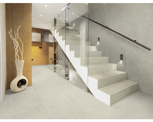 Intrare luminoasă cu scară din piatră, balustradă din sticlă și gresie ceramică.