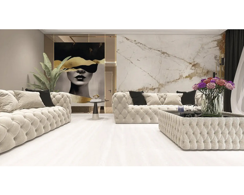 Living luminos cu două canapele capitonate, o măsuță de cafea tapițată, un tablou mural mare și panouri de perete cu aspect de marmură.