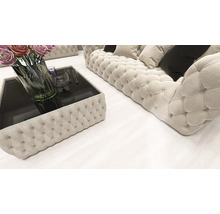 Living modern cu o canapea Chesterfield matlasată și măsuță de cafea asortată pe o pardoseală deschisă cu aspect de lemn.