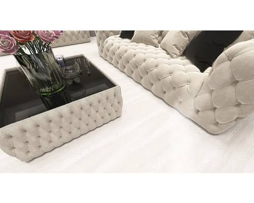 Living modern cu o canapea Chesterfield matlasată și măsuță de cafea asortată pe o pardoseală deschisă cu aspect de lemn.