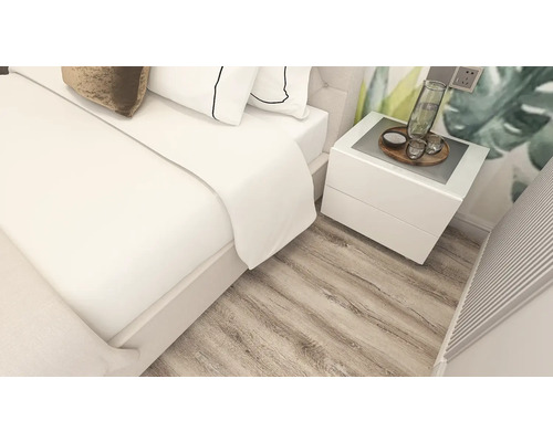 Dormitor luminos cu pardoseală cu aspect de stejar, pat dublu alb și noptieră albă asortată.