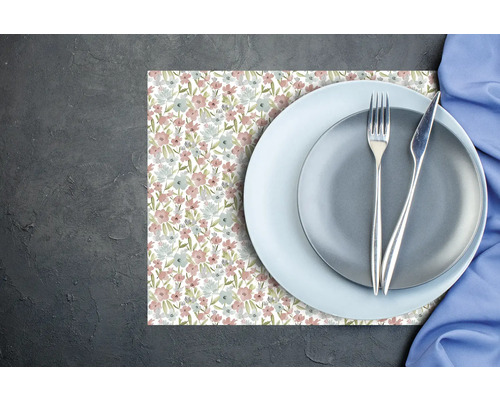 Suport pentru farfurii cu model floral, două farfurii și tacâmuri pe o suprafață închisă și texturată.