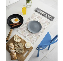 Suport pentru farfurii cu model floral pe o masă albă cu o farfurie gri, mic dejun într-o tigaie, pâine pe un tocător și suc de portocale.