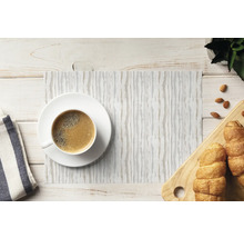 Suport de masă dreptunghiular cu model cu dungi pe o masă din lemn decorată cu o ceașcă de cafea și croissanturi.