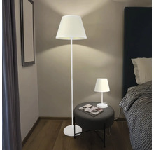 Scenă cu lampă de podea și lampă de masă într-un dormitor.