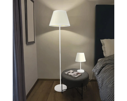 Scenă cu lampă de podea și lampă de masă într-un dormitor.