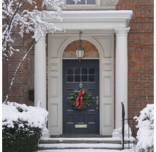 Ușă de intrare a unei case cu o coroană de Crăciun iarna