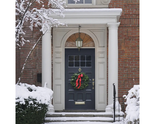 Ușă de intrare a unei case cu o coroană de Crăciun iarna