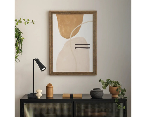 Lucrare de artă decorativă înrămată pe perete deasupra unui dulap negru, cu diverse articole decorative și plante.