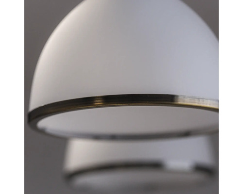 Prim-plan cu o lampă suspendată albă cu inel metalic