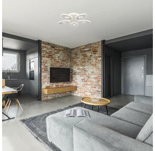 Living modern cu perete de cărămidă, canapea gri, masă și plafonieră albă