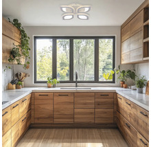 Bucătărie luminoasă cu dulapuri din lemn, fereastră cu vedere la verdeață și lampă de tavan