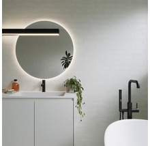 Baie modernă cu oglindă rotundă, chiuvetă, robinet și cadă.