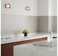 Scenă de bucătărie cu aplice de perete, gresie și ustensile de bucătărie pe blat.