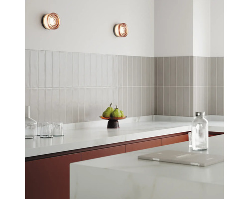 Scenă de bucătărie cu aplice de perete, gresie și ustensile de bucătărie pe blat.