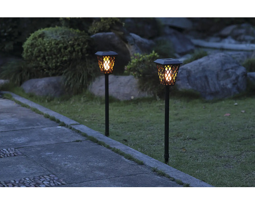 Două lămpi solare iluminează o cărare de grădină.