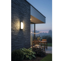 Terasa iluminată cu lampă de perete, masă din lemn și ghirlandă luminoasă în grădină