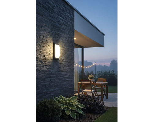 Terasa iluminată cu lampă de perete, masă din lemn și ghirlandă luminoasă în grădină