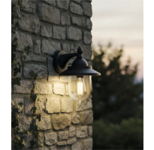 Lumină de perete pentru exterior cu abajur transparent pe un zid de piatră