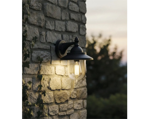 Lumină de perete pentru exterior cu abajur transparent pe un zid de piatră