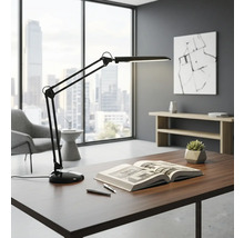 Birou cu lampă de birou cu braț mobil, carte și pixuri într-un birou luminos.