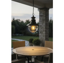 Lampa suspendată metalică cu glob de sticlă transparentă deasupra unei mese de grădină