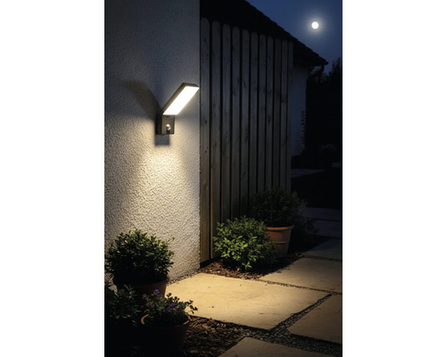 Lumină modernă de exterior cu LED, cu senzor de mișcare pe un perete al casei pe timp de noapte