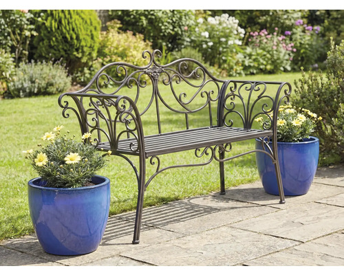 Bancă de grădină metalică ornamentată cu ghivece de flori pe o terasă de grădină