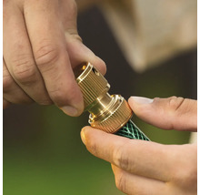 Conector de furtun din alamă montat pe un furtun de grădină.
