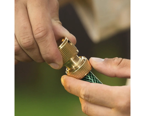 Conector de furtun din alamă montat pe un furtun de grădină.