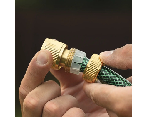 Mâini care montează un conector de furtun din alamă pe un furtun de grădină verde.