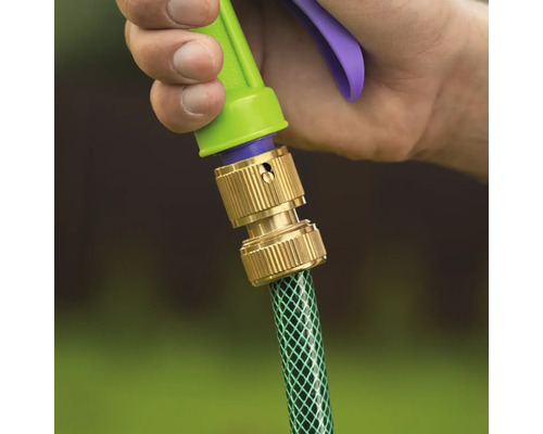 Conector de furtun din alamă care conectează un furtun de grădină la un pulverizator, ținut de o mână.
