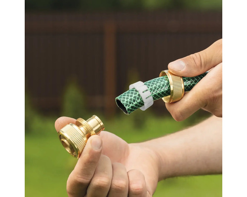 Mâini care montează un conector de furtun din alamă pe un furtun de grădină.