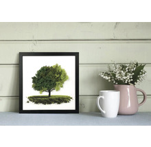 Tablou pătrat din mușchi în ramă neagră cu motiv de copac, lângă o cană albă și o vază roz cu lăcrămioare.