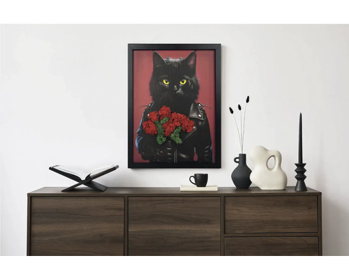 Tablou modern înrămat cu o pisică neagră în jachetă de piele și flori deasupra unei comode închise la culoare cu obiecte decorative.