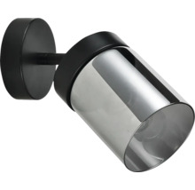 Spot de perete modern cu bază metalică neagră și abajur cilindric din sticlă fumurie.