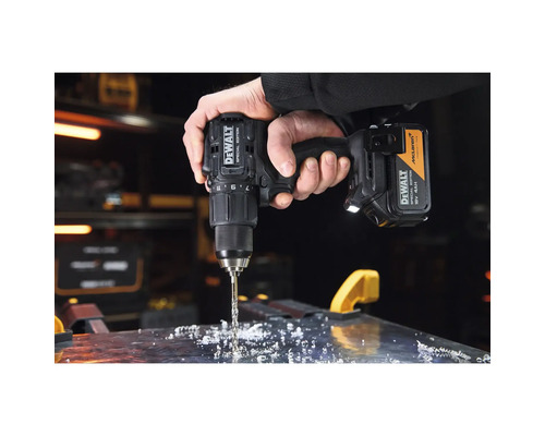 Mașină de găurit cu acumulator DeWALT McLaren Special Edition găurind o suprafață metalică cu șpan într-un atelier.