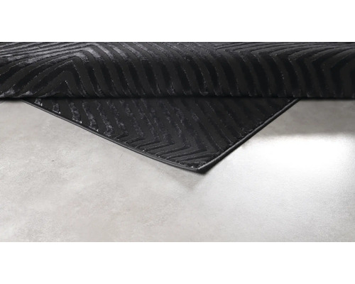 Covor negru cu model grafic în zigzag și colț îndoit.