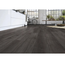Pardoseală laminată cu aspect de lemn închis într-o cameră modernă, luminoasă, cu insulă de bucătărie și fereastră mare.