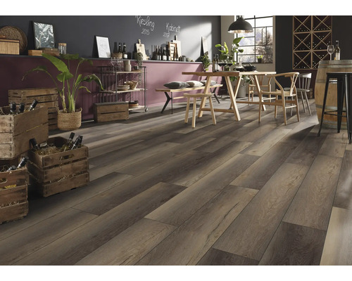 Pardoseală laminată închisă la culoare cu aspect de lemn într-o încăpere rustică cu masă de lemn, scaune și lăzi de vin. Atmosferă luminoasă.